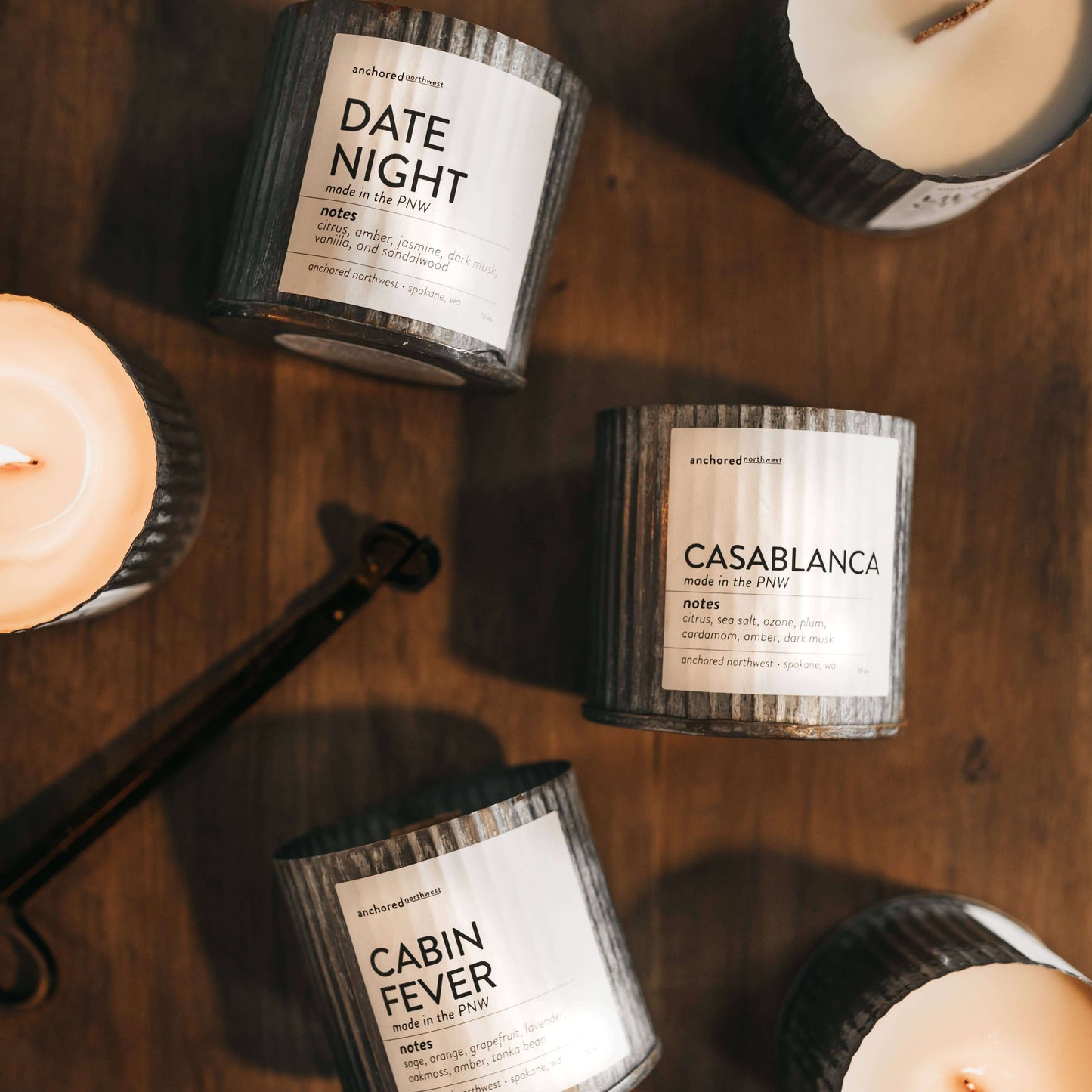 Assorted rustic candles labeled Date Night, Casablanca, and Cabin Fever, featuring unique fragrance notes.