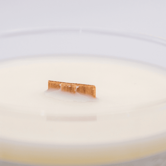 Close up of a clear glass soy candle with a wood wick.