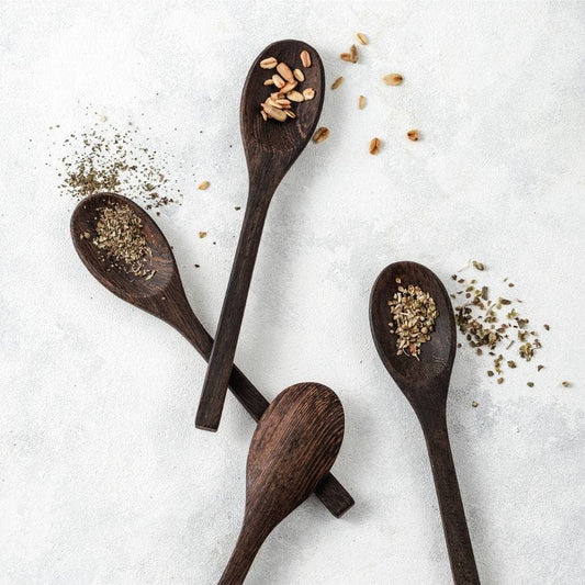 Handcrafted coconut wooden spoons with spices on a light background, showcasing sustainable and artisanal design.