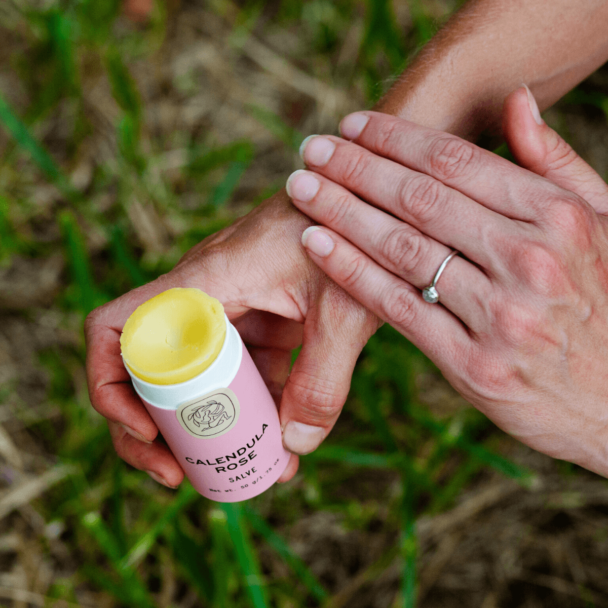 Hand applying Calendula Rose salve from eco-friendly tube for skin nourishment and care.