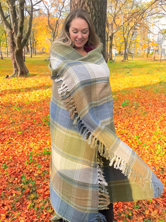 Woman wrapped in a plaid blanket in an autumn park