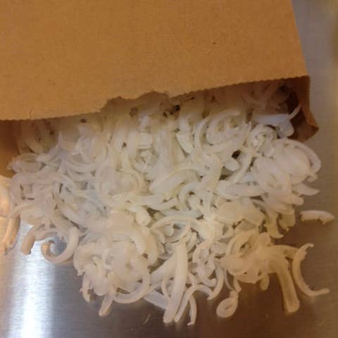 Shredded natural soap flakes spilling from a cardboard box on a silver surface.