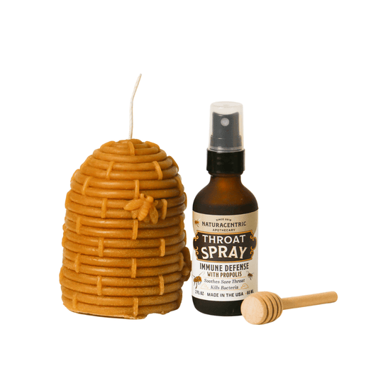 Immune Defense Throat Spray with Propolis & Honey alongside a honeycomb candle and honey dipper.