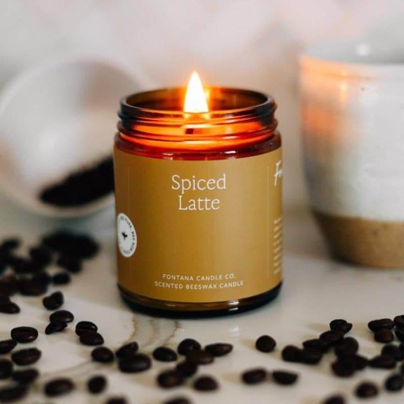 Spiced Latte essential oil beeswax jar candle with glowing flame and coffee beans around it.