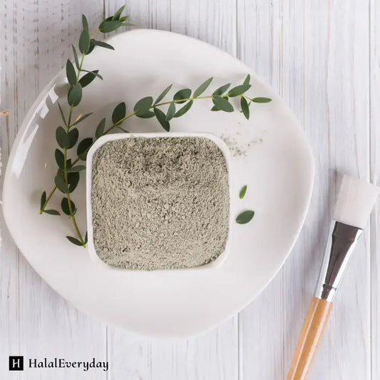 Bentonite clay in a square dish with green leaves, perfect for deep pore cleansing and skincare treatments.