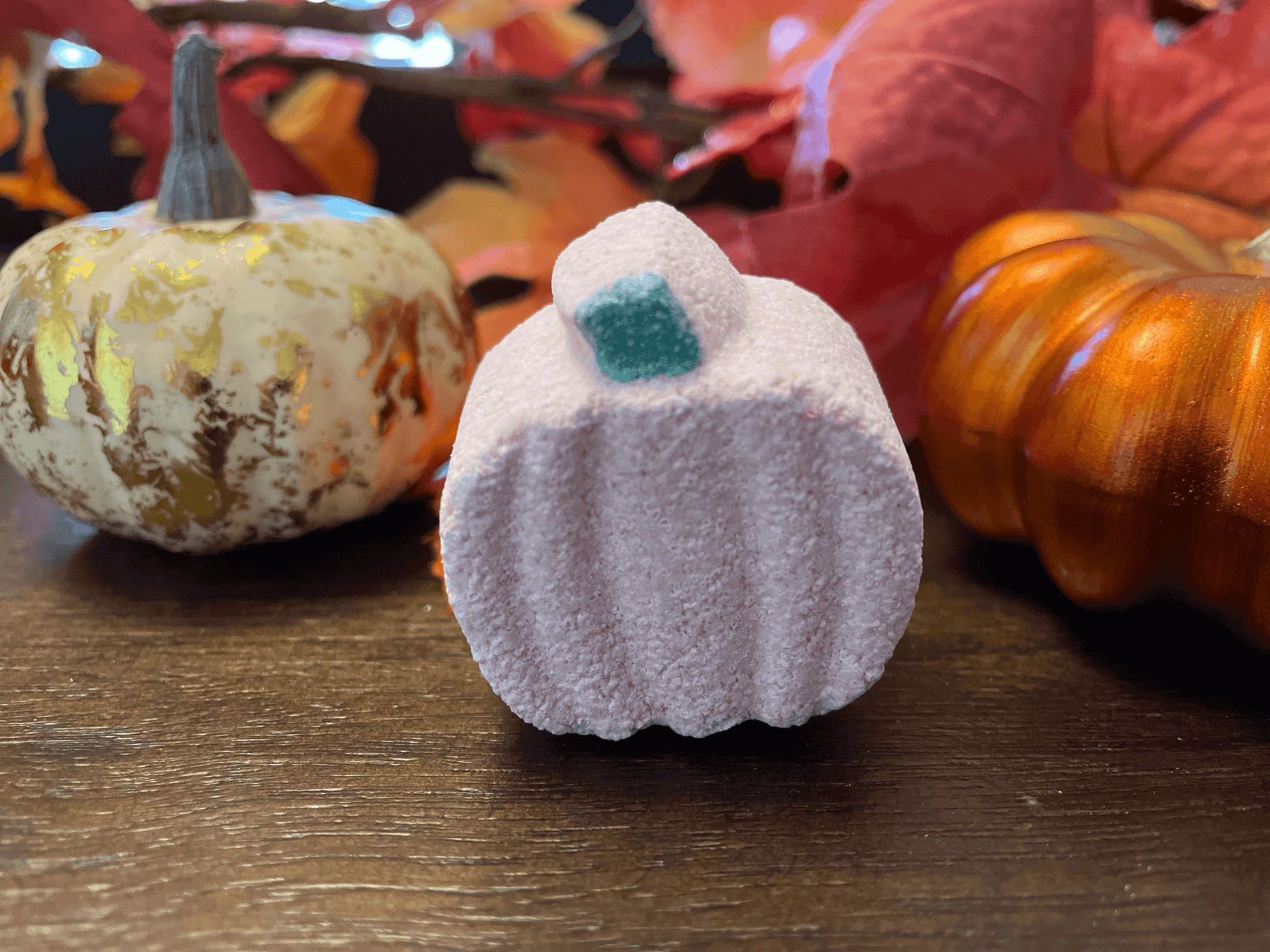Natural mini pumpkin bath bomb with decorative pumpkins and fall leaves in the background.