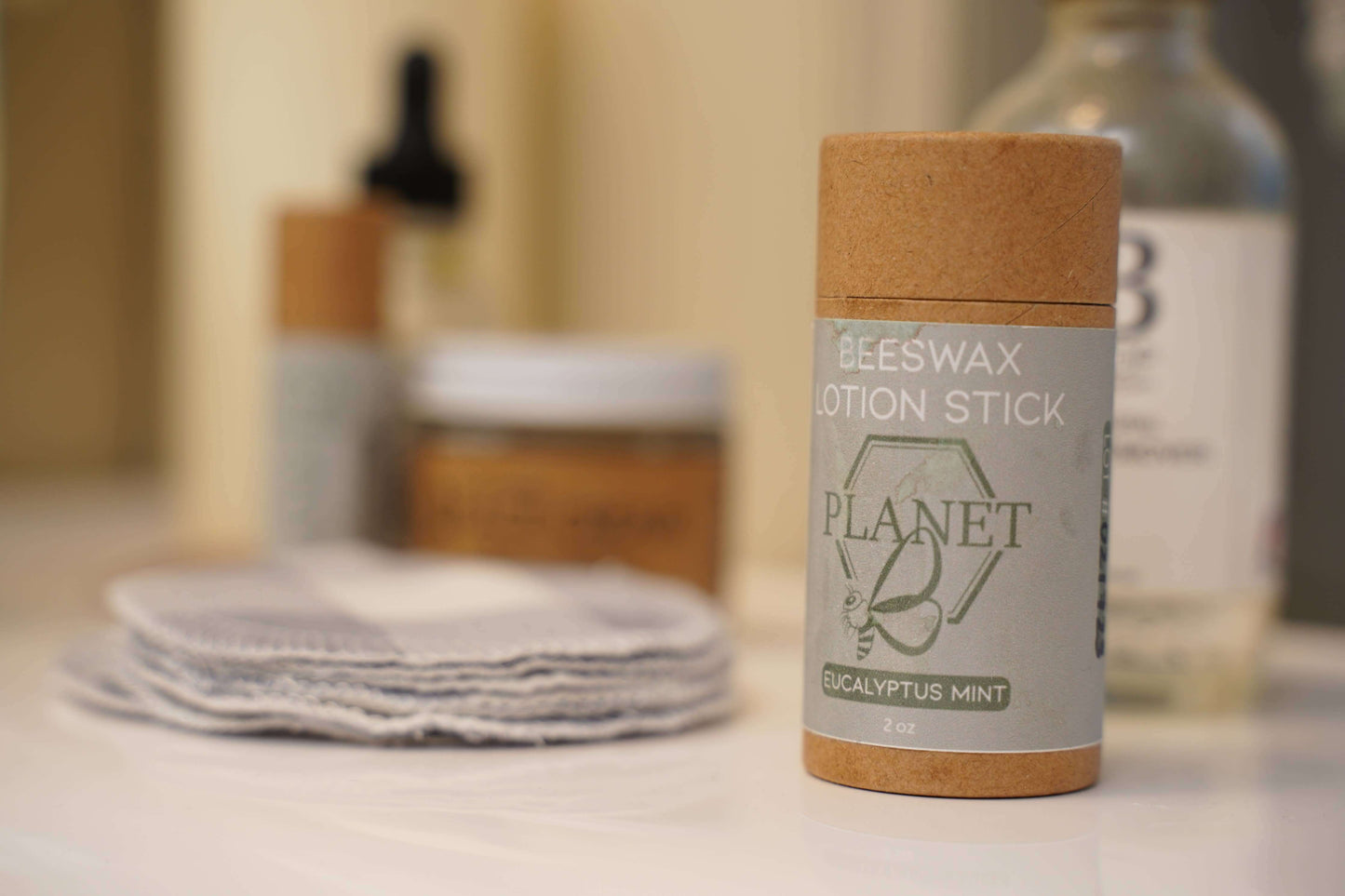 Beeswax Lotion Stick - Eucalyptus Mint in a kraft paper tube on a bathroom counter.
