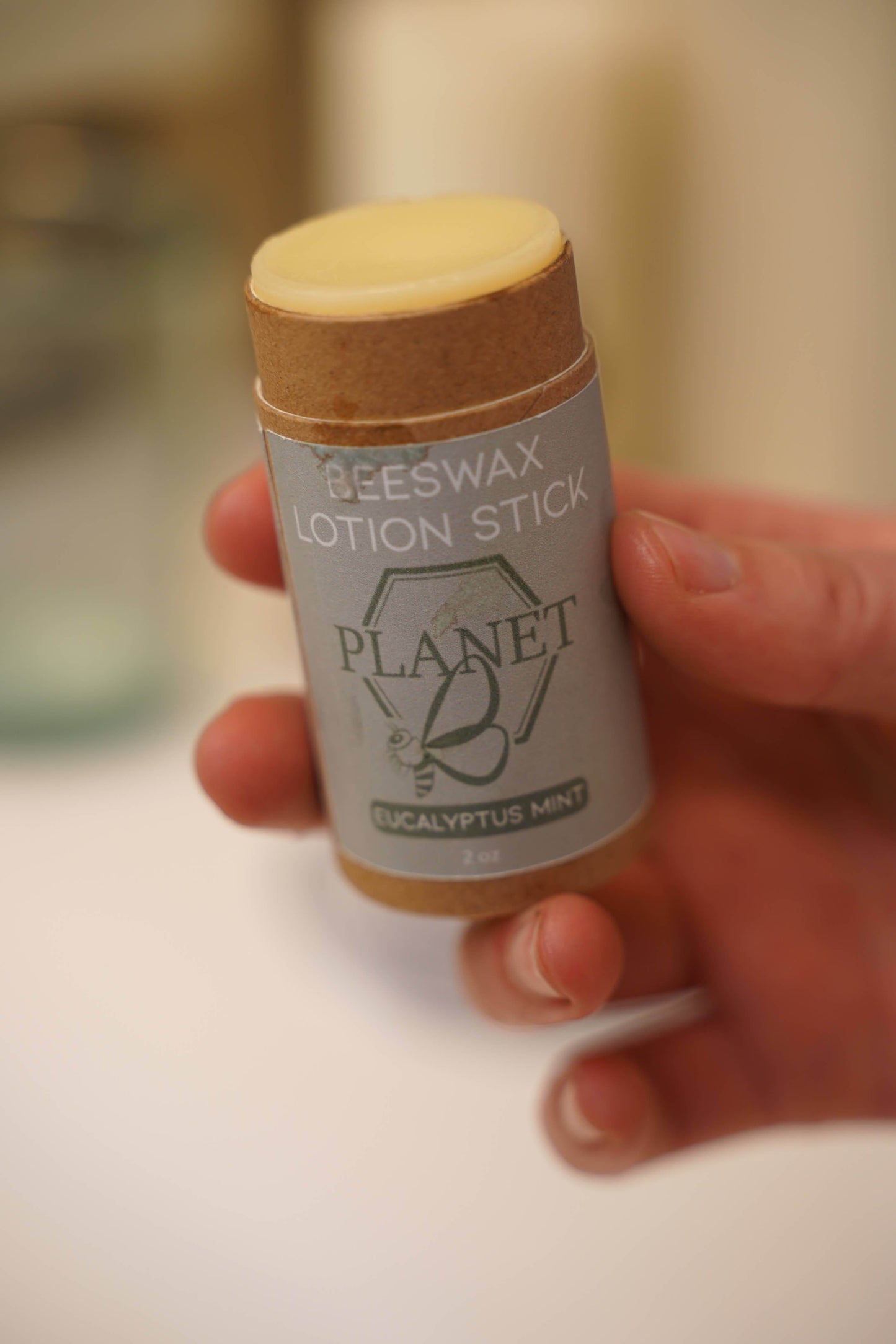 Beeswax Lotion Stick - Eucalyptus Mint in a kraft paper tube held in hand, perfect for moisturizing on the go.