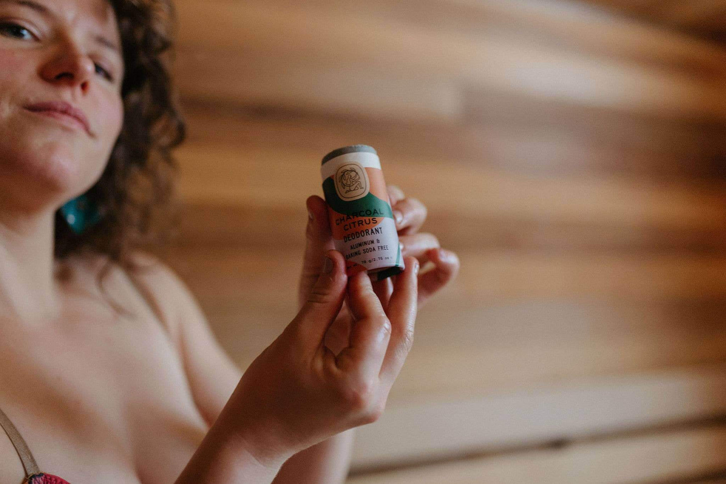 A girl holding an eco-friendly, non toxic charcoal citrus deodorant stick.