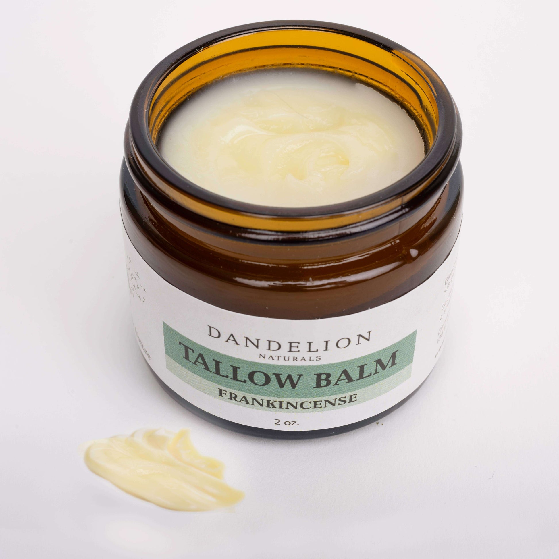 Glass jar of Dandelion Naturals firm Tallow Balm with Frankincense, featuring a creamy texture.