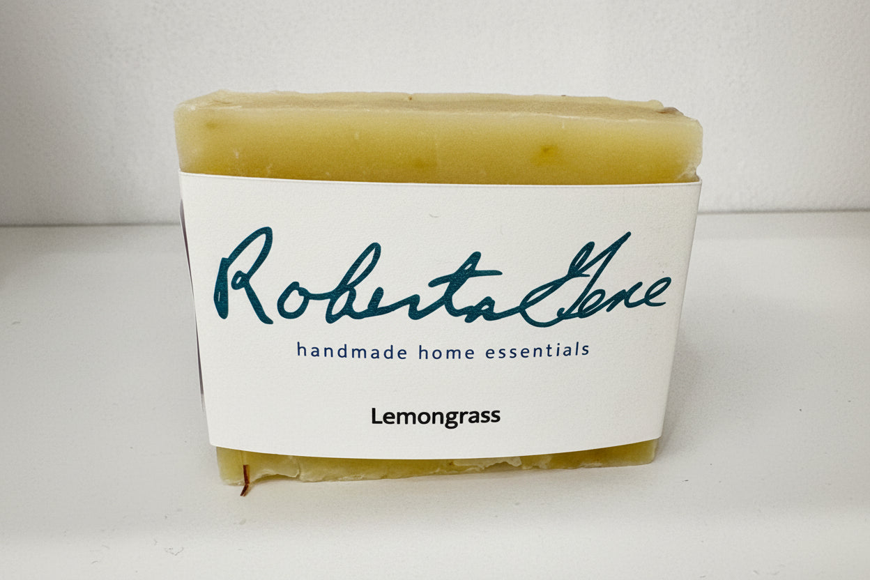 Bar of soap with a label reading 'Roberta Gene handmade home essentials Lemongrass' on a white background.