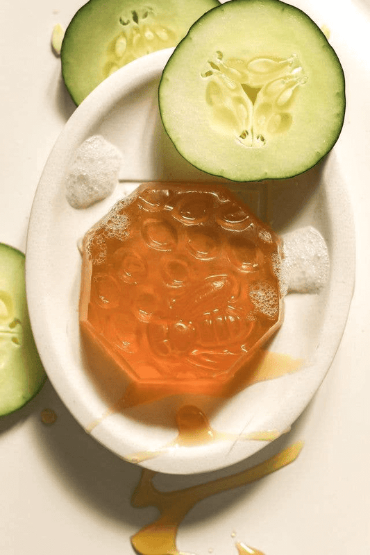 honey cucumber melon soap on a white soap dish with drizzled honey and cucumbers