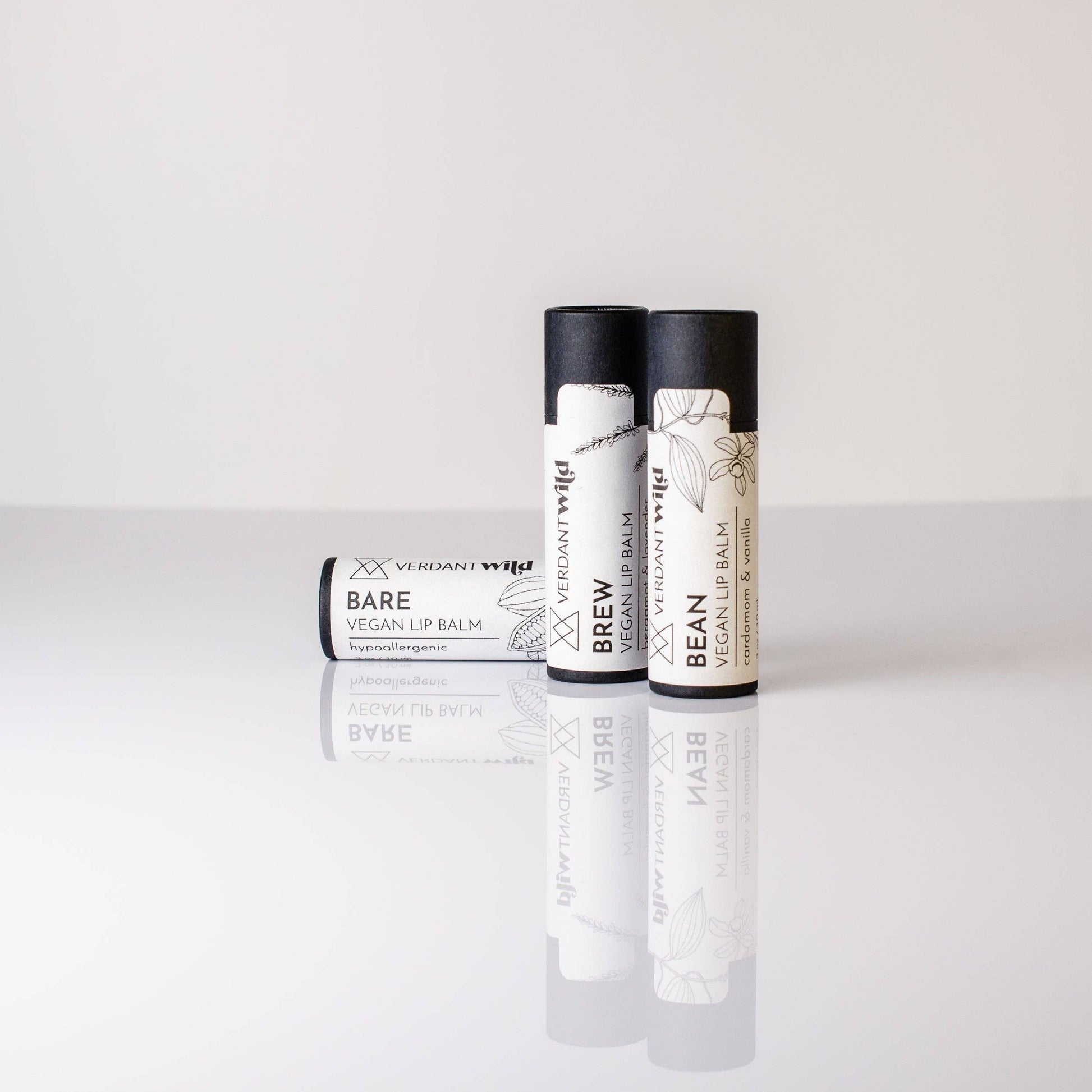Three vegan lip balms in black biodegradable tubes with white labels.