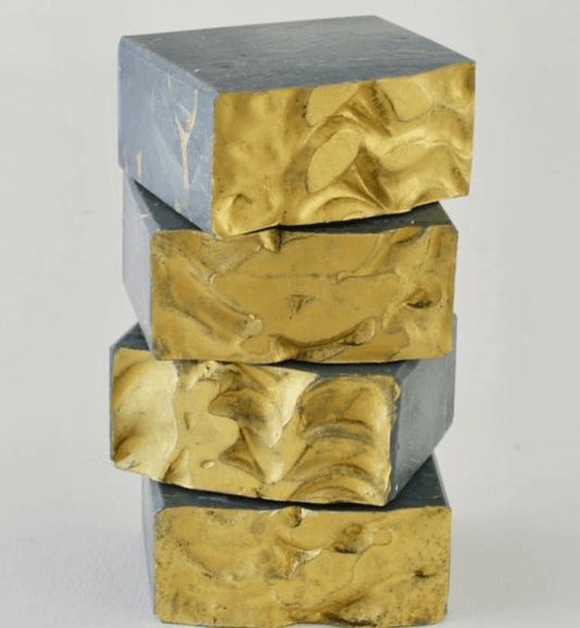 Four organic, black gold soap bars stacked on top of each other.