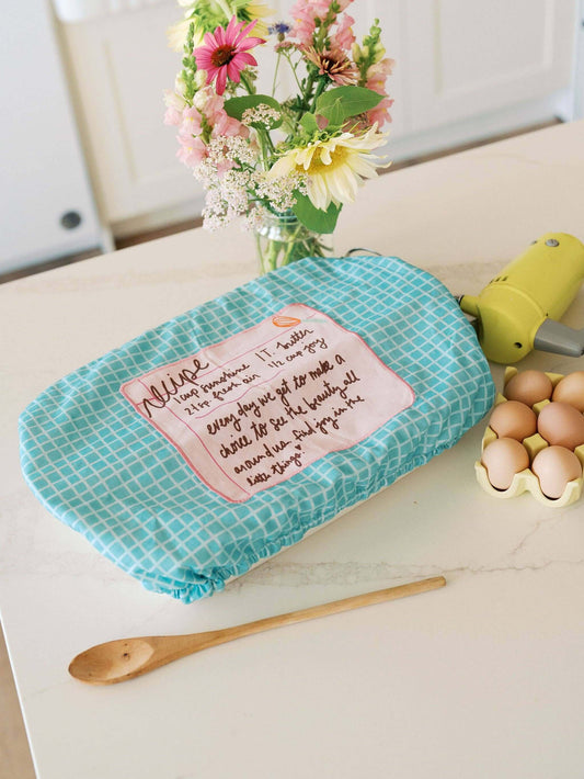 Recipe for a Happy Heart 10x14 Baking Dish Cover | Baking on a kitchen countertop with flowers and eggs.