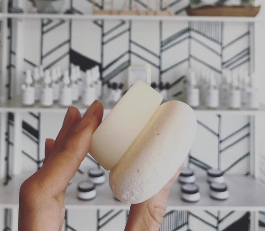 A hand holding up shampoo and conditioner bars in invigorate scent.