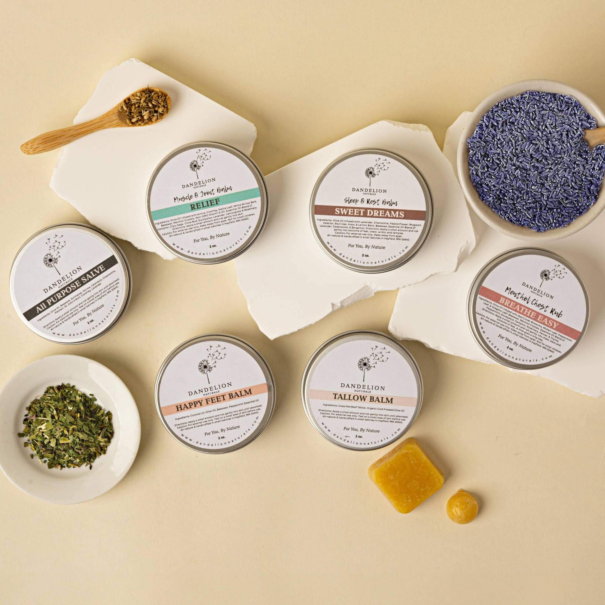 Dandelion Tallow Balm and other natural moisturizers displayed with herbs and lavender for skincare.