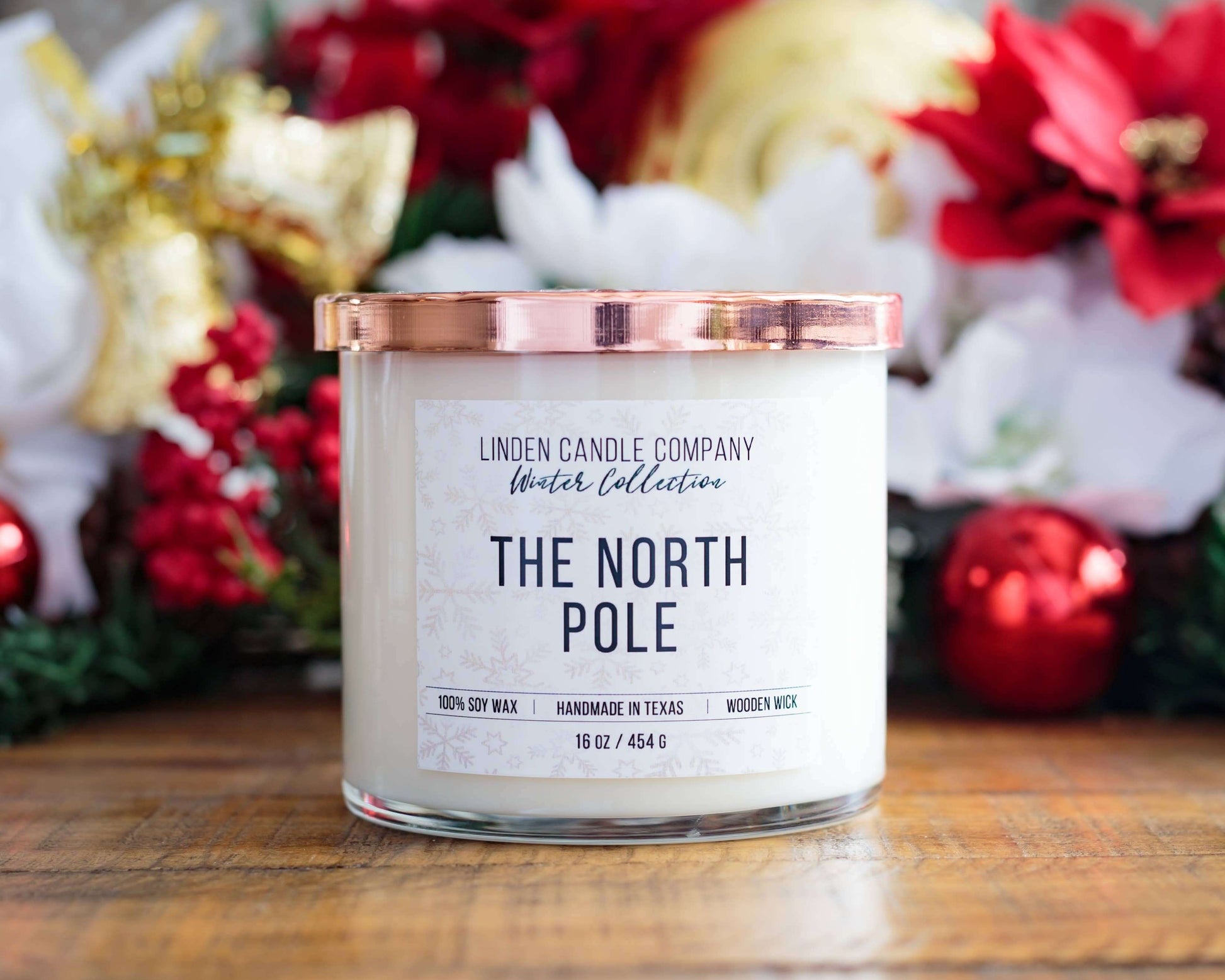 The North Pole 16oz Seasonal Winter Soy Candle in a festive setting with a copper lid and decorative holiday backdrop.